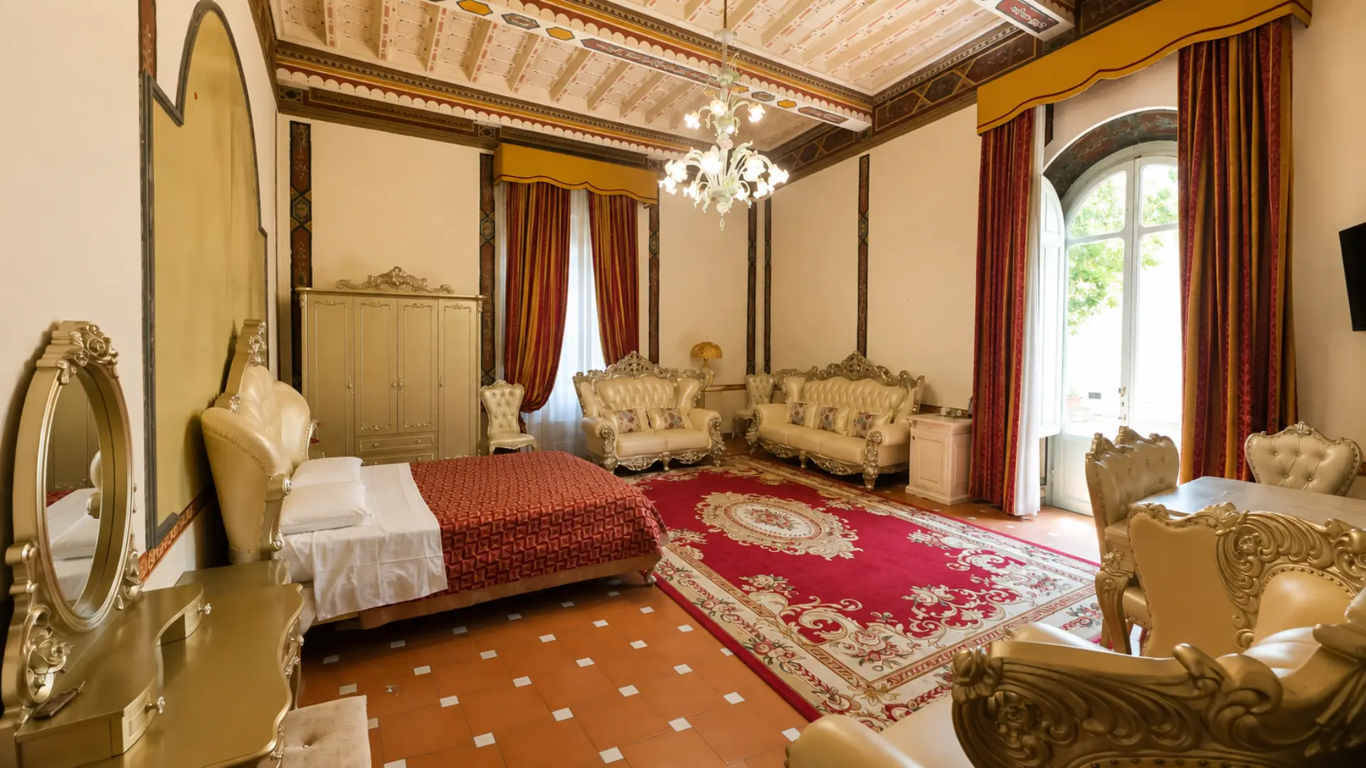 Il salotto della Junior Suite con i divani dorati e la portafinestra ad arco che dà sul parco