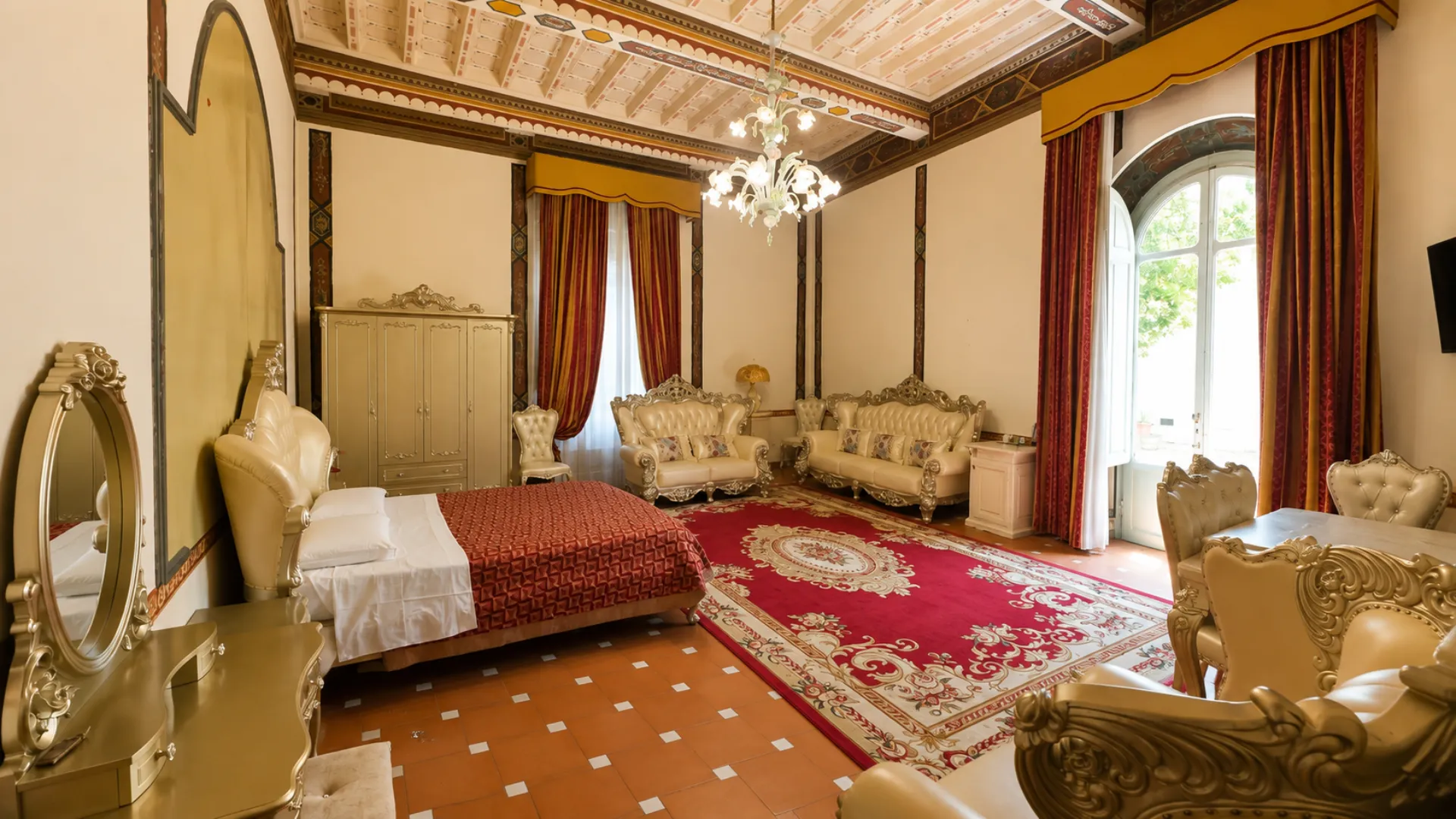 Il salotto della Junior Suite con i divani dorati e la portafinestra ad arco che dà sul parco