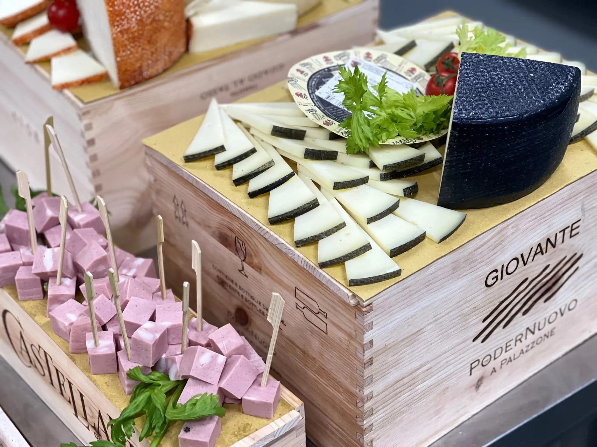 Il banco dell'aperitivo su casse di legno da vino: taglieri di formaggi, salumi a spiedino e vassoi apparecchiati