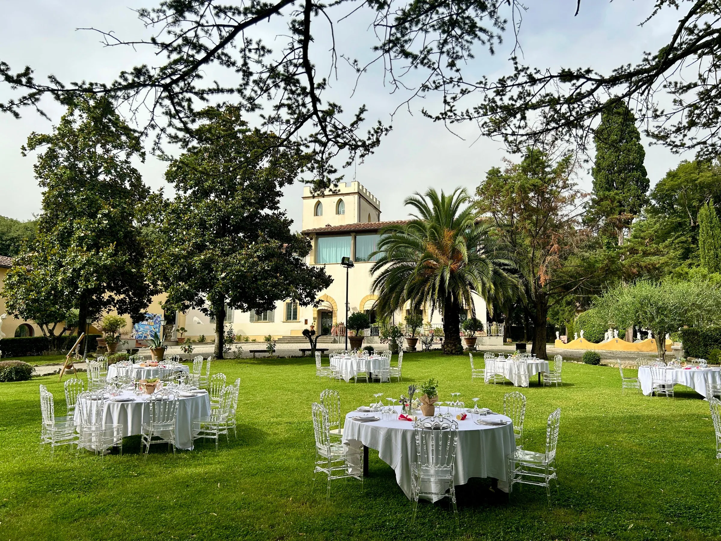 Il prato davanti alla serra allestito a banchetto, con i tavoli rotondi apparecchiati e la villa sullo sfondo