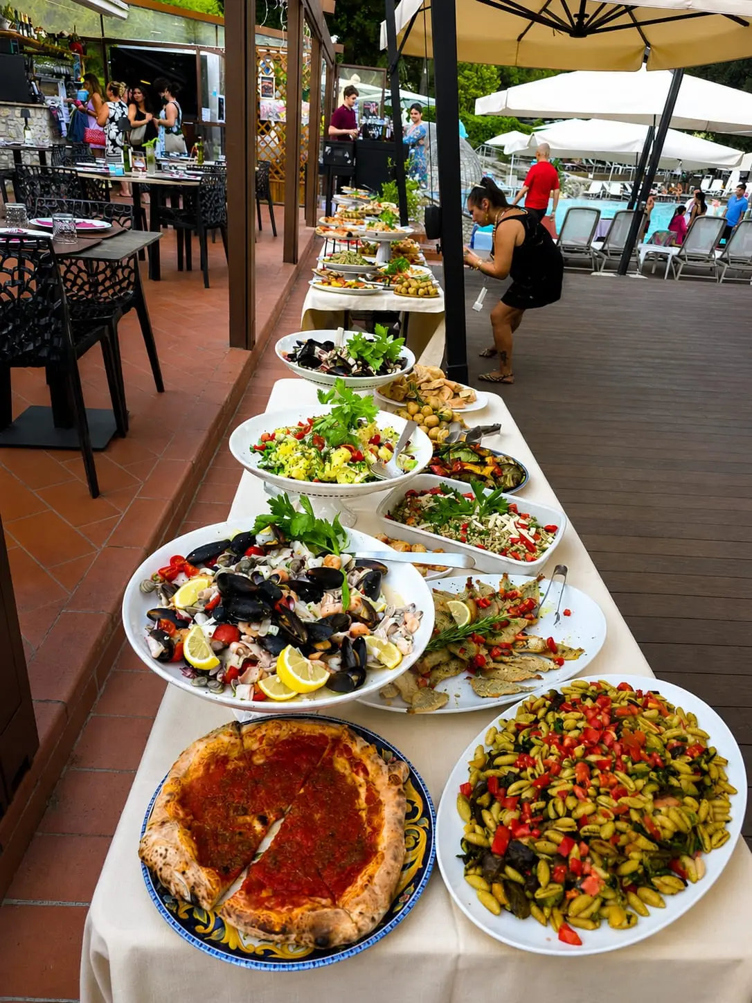 Il buffet dell'apericena a bordo piscina: pizza, pasta fredda, frutti di mare e verdure