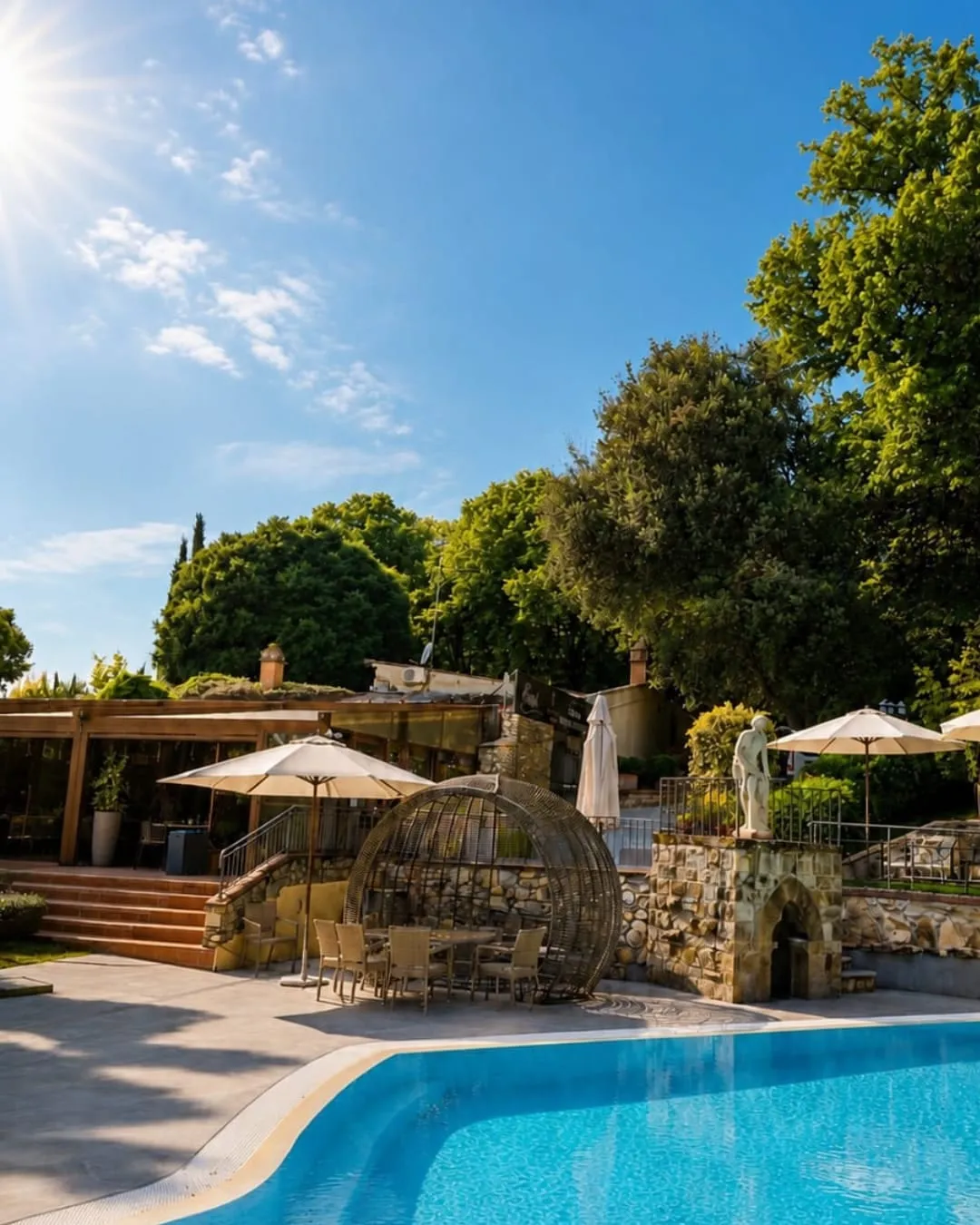Il bordo piscina con la pergola del bar, i tavoli all’ombra e la poltrona a sfera