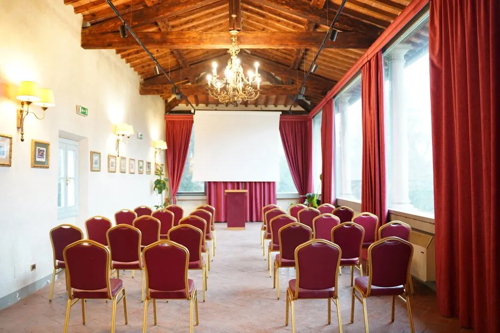 La Sala Eventi allestita a platea: sedie rosse e oro in file davanti al podio e allo schermo