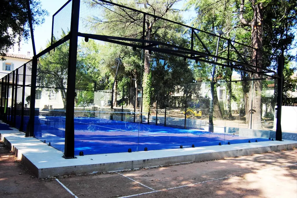 Il campo da padel con il fondo blu, fra i pini del parco